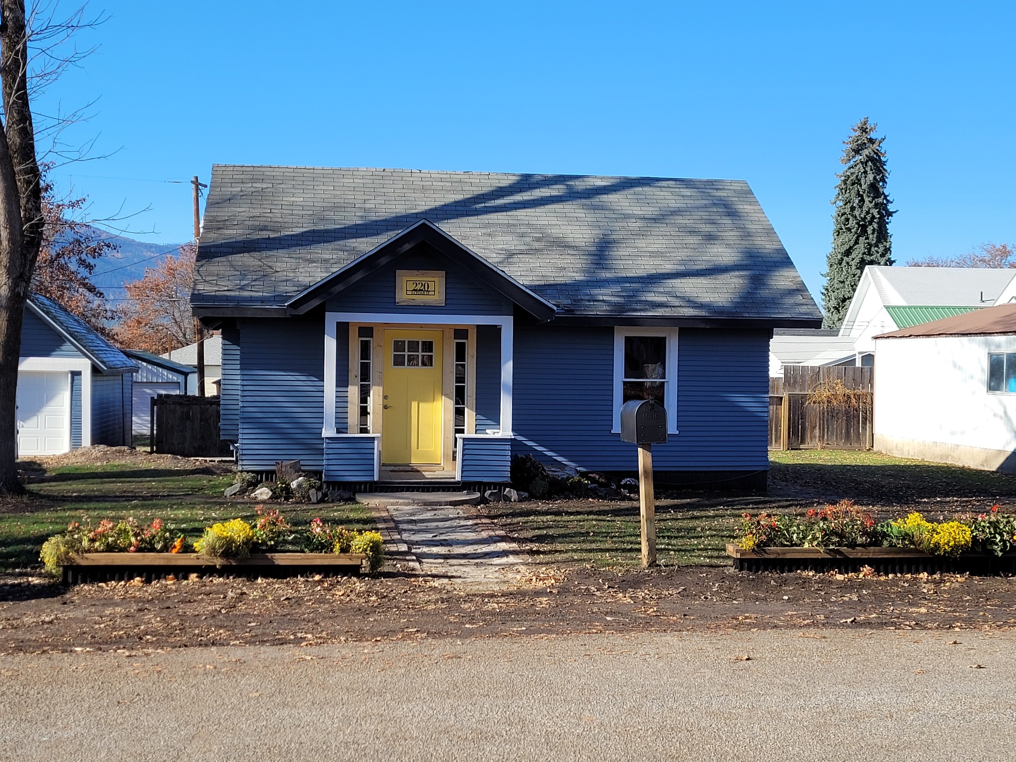 The first project house restored with blue siding, white trim, and a welcoming front porch